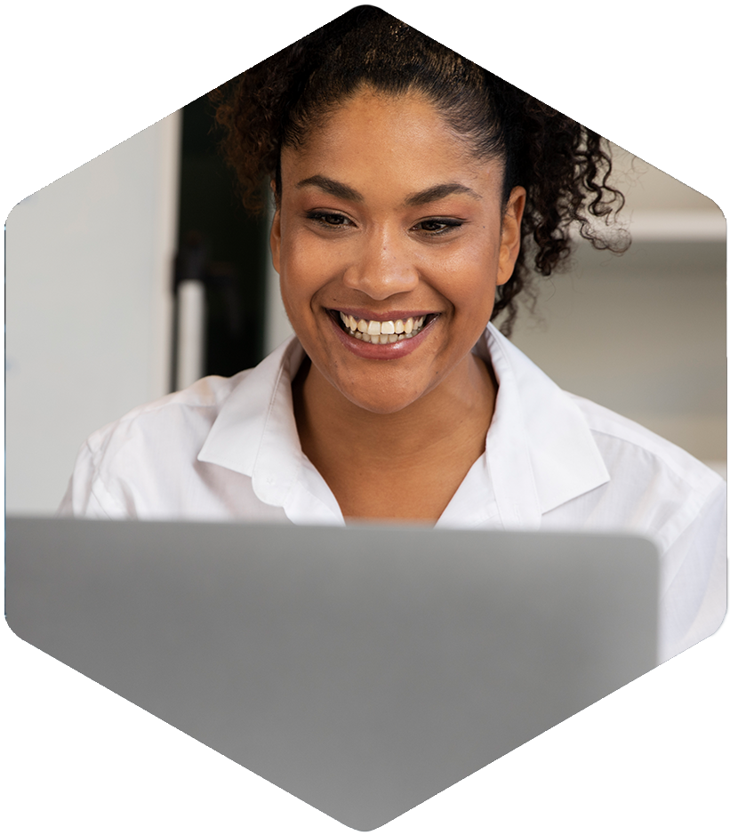 A curly-haired person smiles at their laptop, engaging with Simulations Plus digital learning tools.