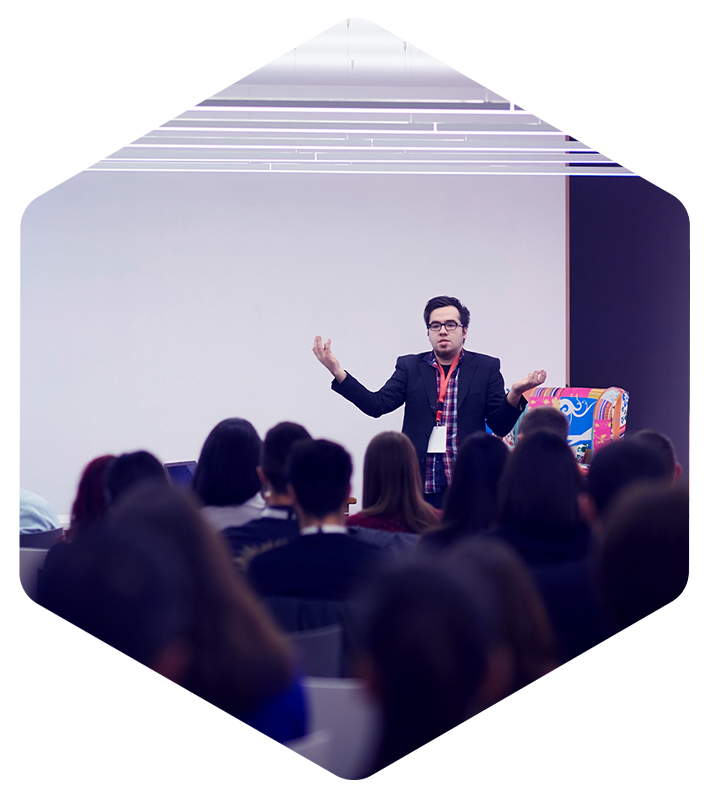 In a modern room, a speaker presents Simulations Plus QSP software to an attentive audience.